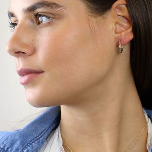 lady wearing gold open hoop stud earrings with oblong coloured crystals in pink, green and lilac