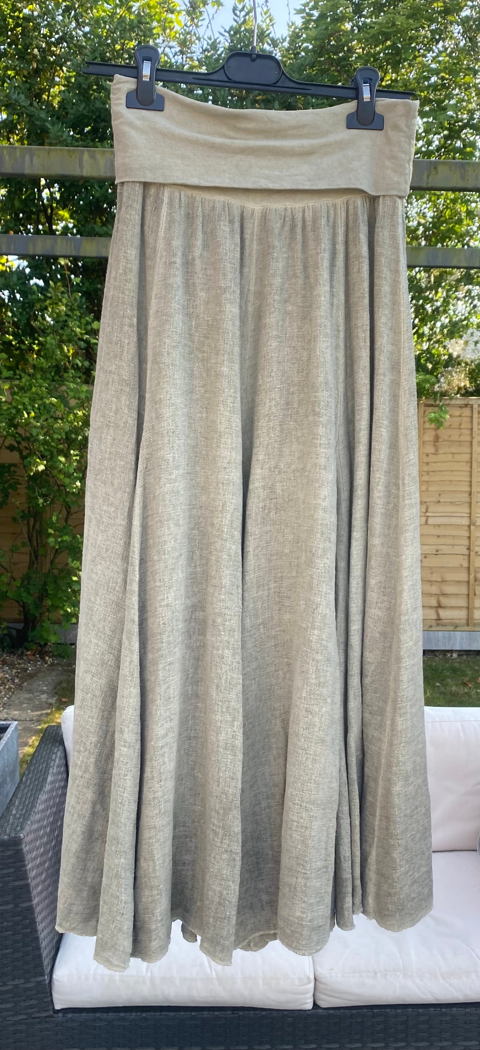 Khaki Sugarbabe maxi skirt in linen hanging on a hanger in a garden 