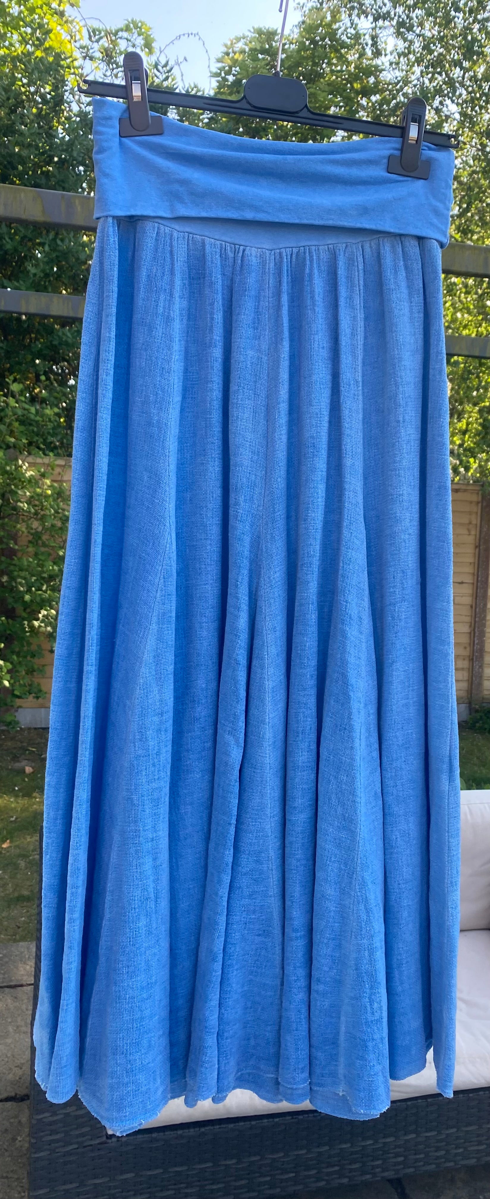 Cornflower blue washed linen maxi skirt with wide waistband hanging up outside in garden 