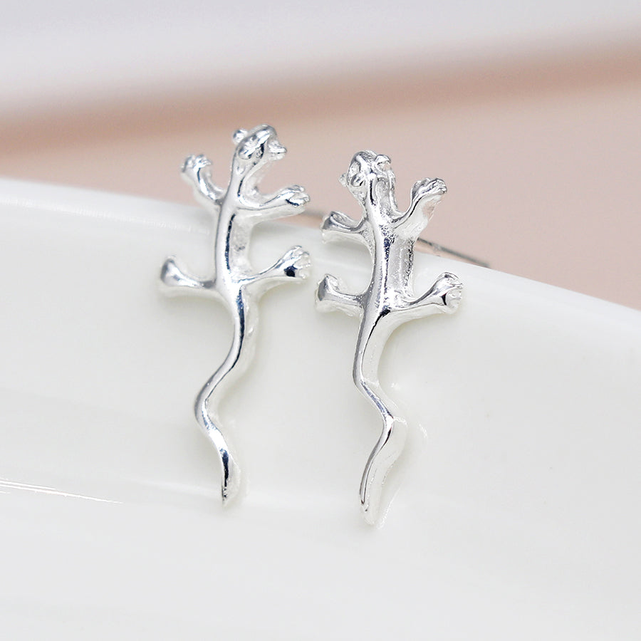 A photo of a pair of sterling silver stud earrings in a gecko shape 