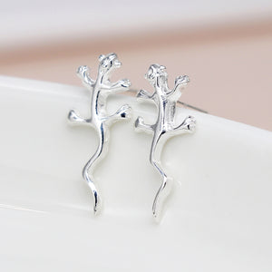 A photo of a pair of sterling silver stud earrings in a gecko shape 