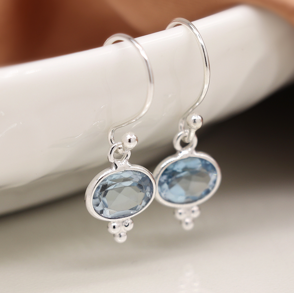 Photo of a pair of sterling silver drop earrings with faceted topaz and three small silver dot detail at base and fine silver hooks