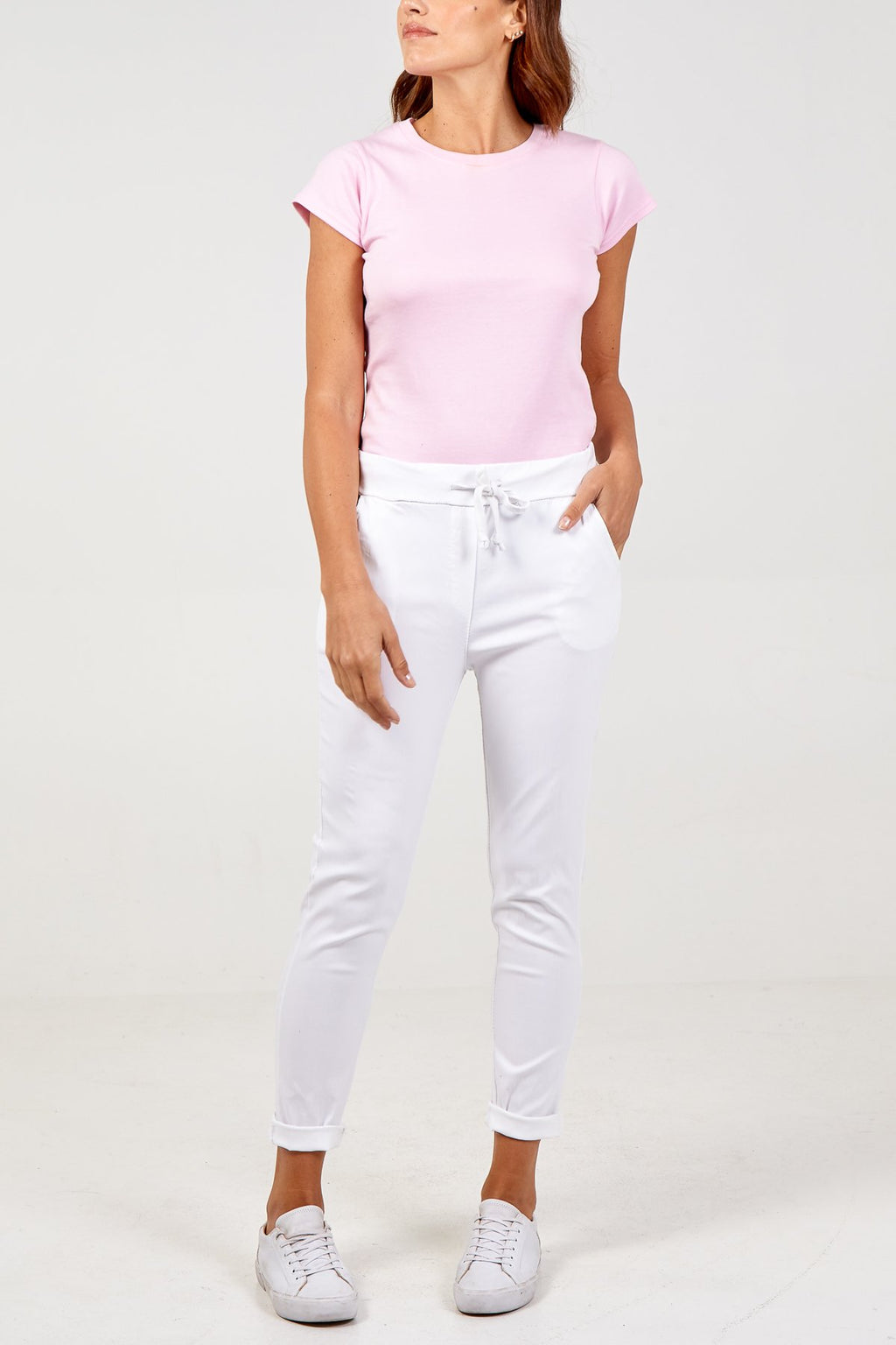 A model wearing plain white colour magic trousers and a pink t shirt and trainers 