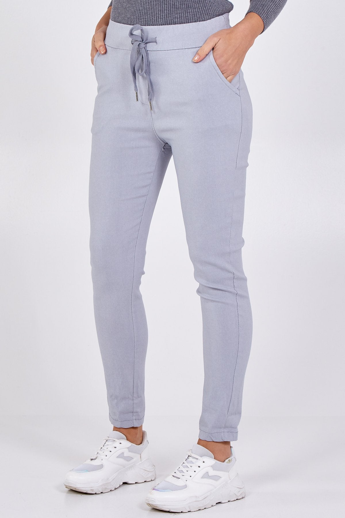 A model wearing plain light grey colour magic trousers and a grey top and trainers 