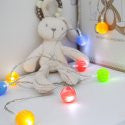 Multicolour ball fairy lights next to a cream teddy