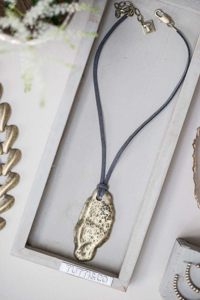 Gold textured flat stone shaped pendant with inset crystals on leather chain